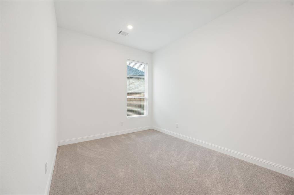 This secondary room features freshly painted white walls and soft carpet flooring, with a single window providing natural light.