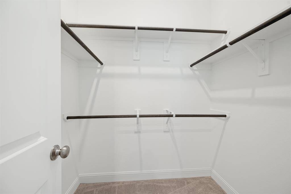This is a spacious walk-in closet with multiple hanging rods and a neutral color palette, perfect for organizing clothes and accessories.