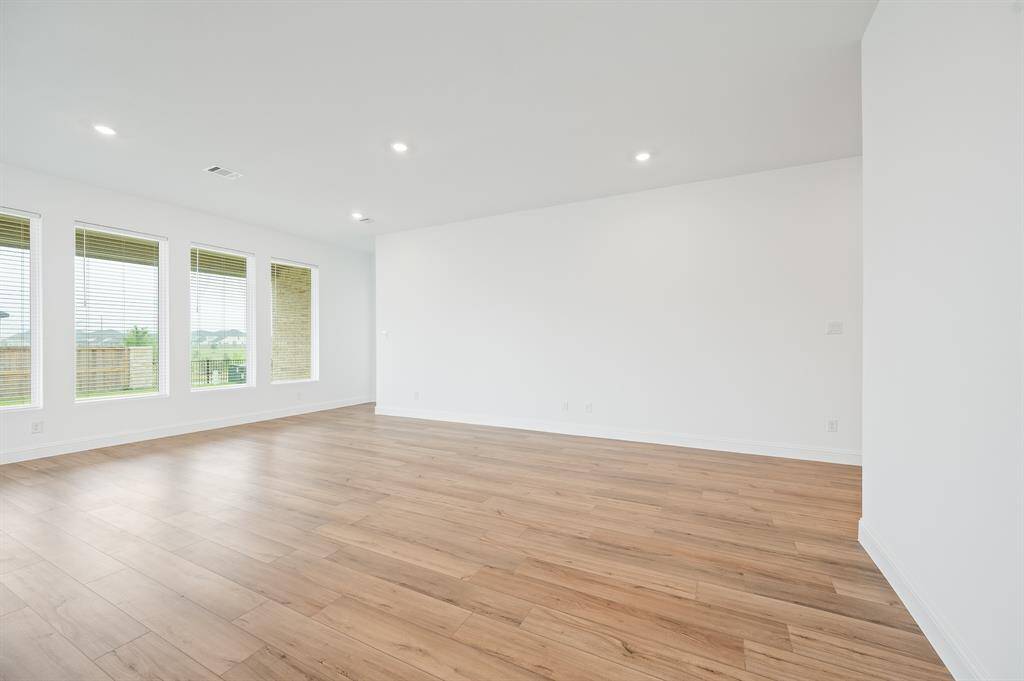 Bright, spacious room with large windows and hardwood floors, perfect for natural light and open living.