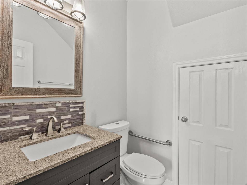 First level 1/2 bath with granite counter, sleek backsplash, and tile flooring