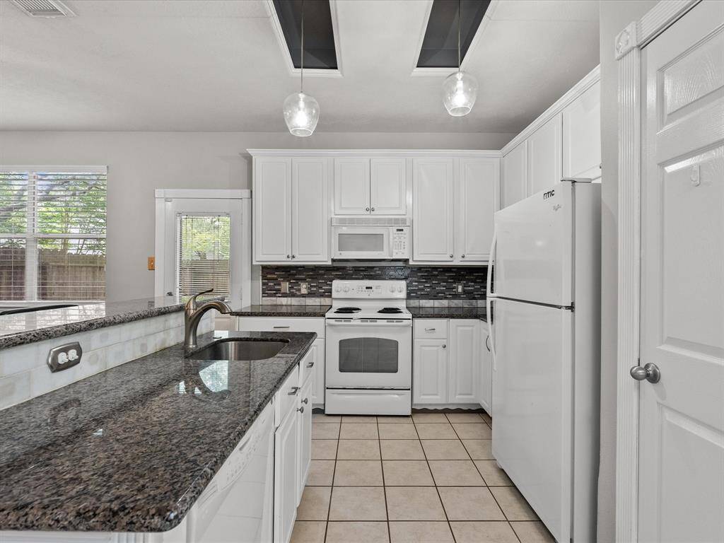 Upgraded granite countertops and sleek glass like backsplash, with decor lighting enhance the kitchen area.