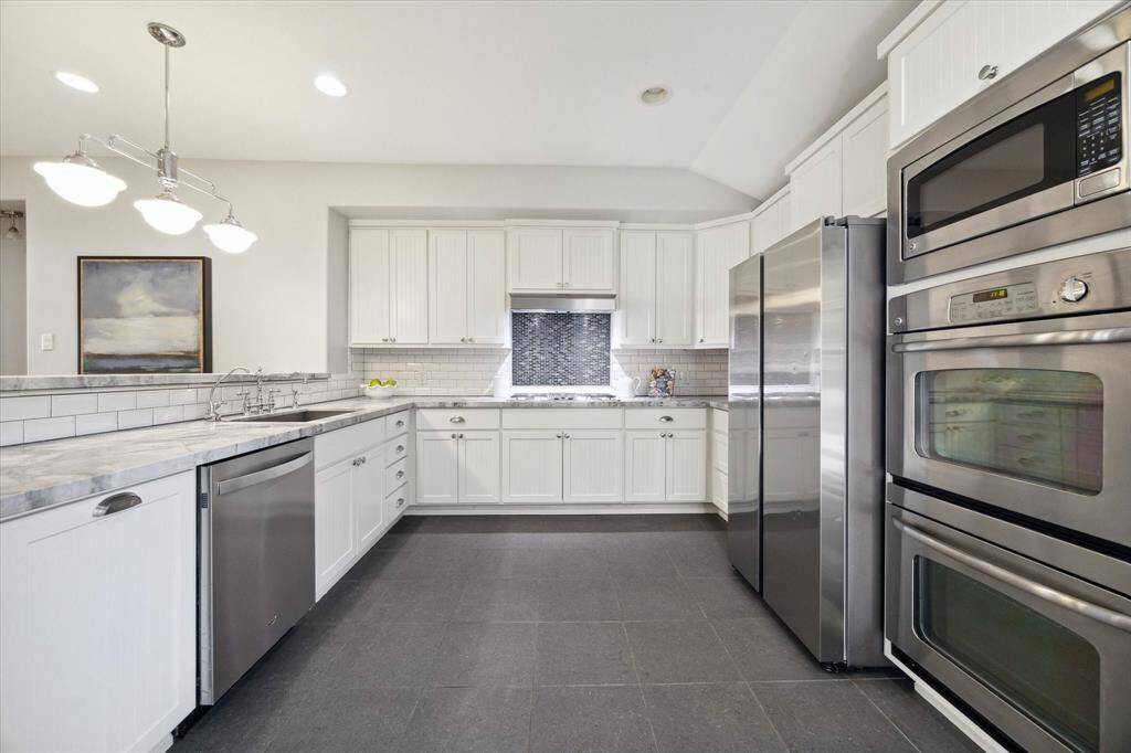 KITCHEN- Spacious kitchen with double ovens and a gas cooktop. Quartzite counters and a large breakfast bar.