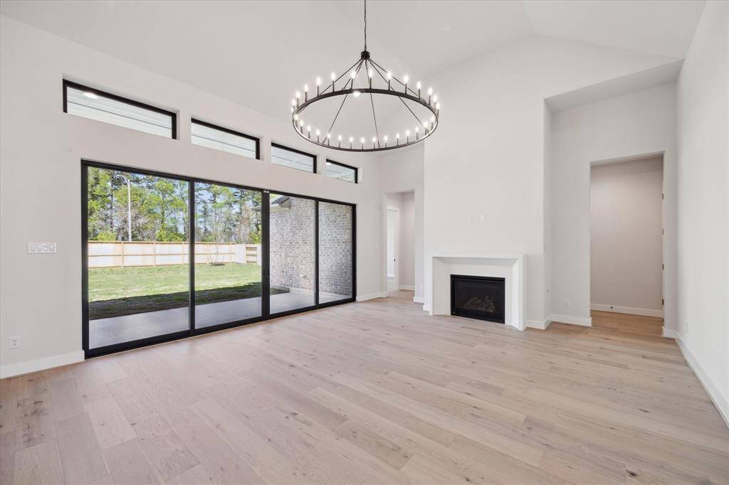The Living Area has a gas fireplace, soaring ceilings, stunning light fixture, and sliding glass doors that lead to the Back Porch and huge Backyard