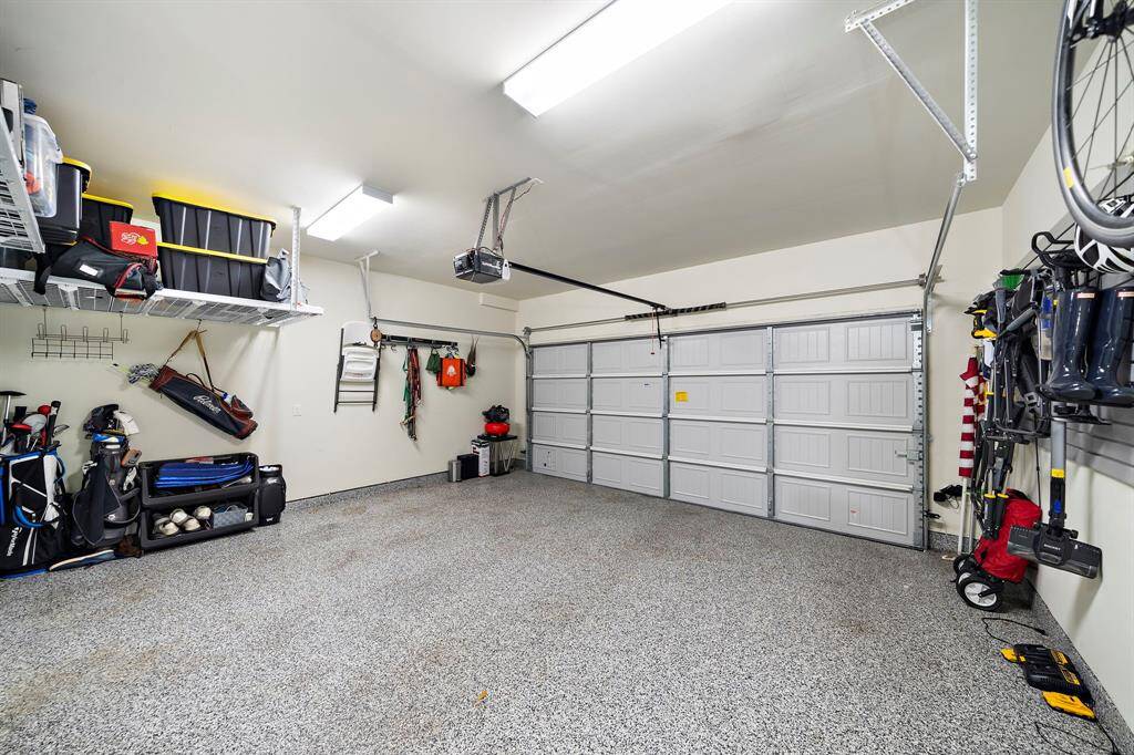 The two car garage has been upgraded with epoxy flooring and mounted shelving for plenty of storage.