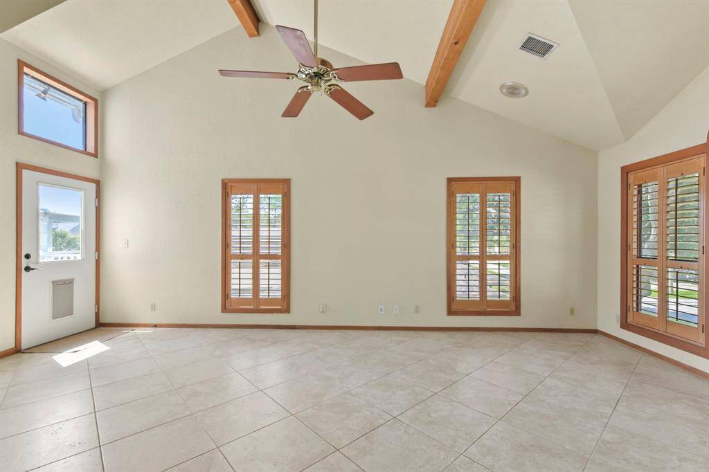 The den features soaring ceilings with elegant wooden beams.