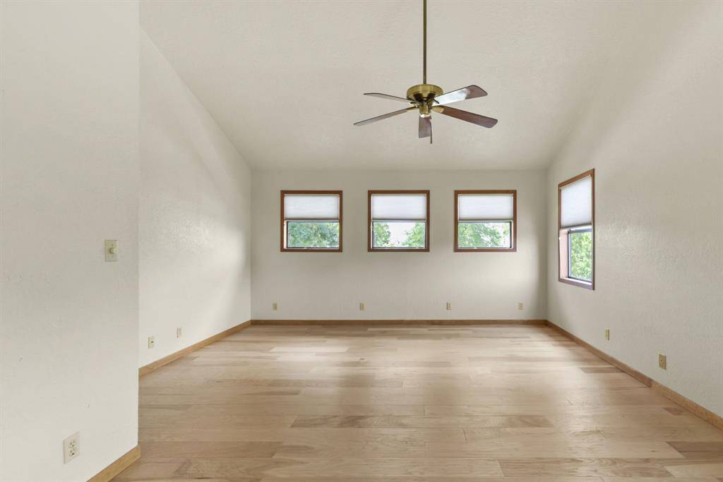 Spacious primary room with high ceilings, abundant natural light, and stylish hardwood flooring.