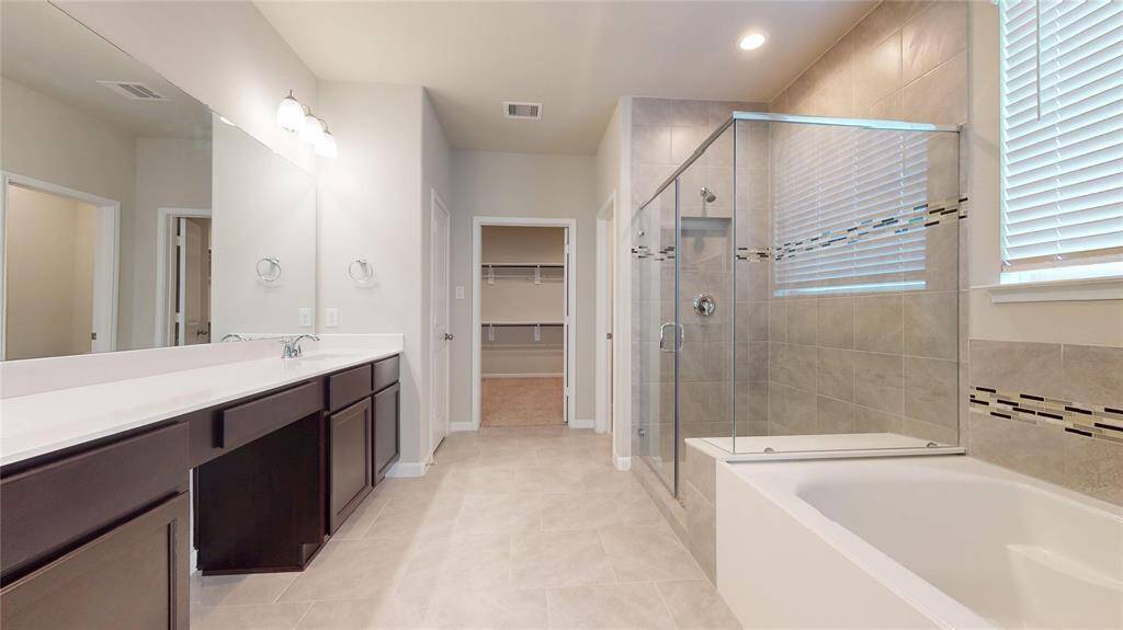 The primary, ensuite bathroom has a very large vanity with two sinks, large stand-alone shower and a soaker tub.  In the background is the walk-in closet.