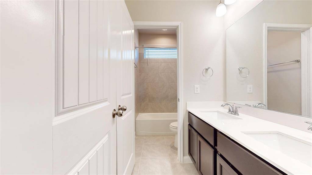 Hall bath between bedrooms #3 and #4.  Vanity with two sinks and separate tub/shower and toilet area.