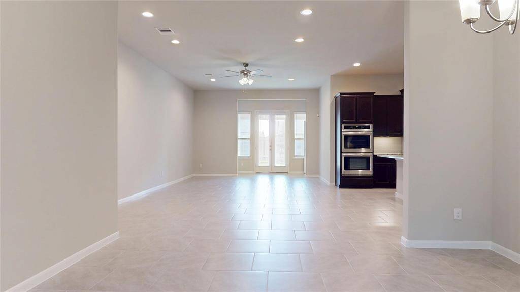 View from the foyer looking toward the dining area, kitchen and family room. Large, modern tile floors throughout the common areas make for easy maintenance.