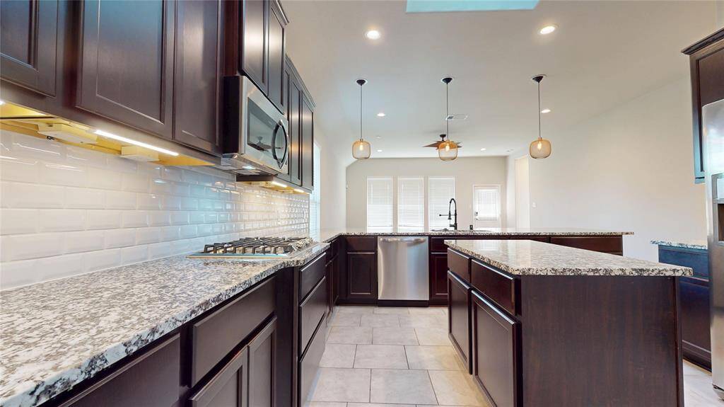 View of the kitchen from the butler's pantry.  Granite countertops, stainless steel appliances, built-in microwave, double oven and subway tile backsplash.