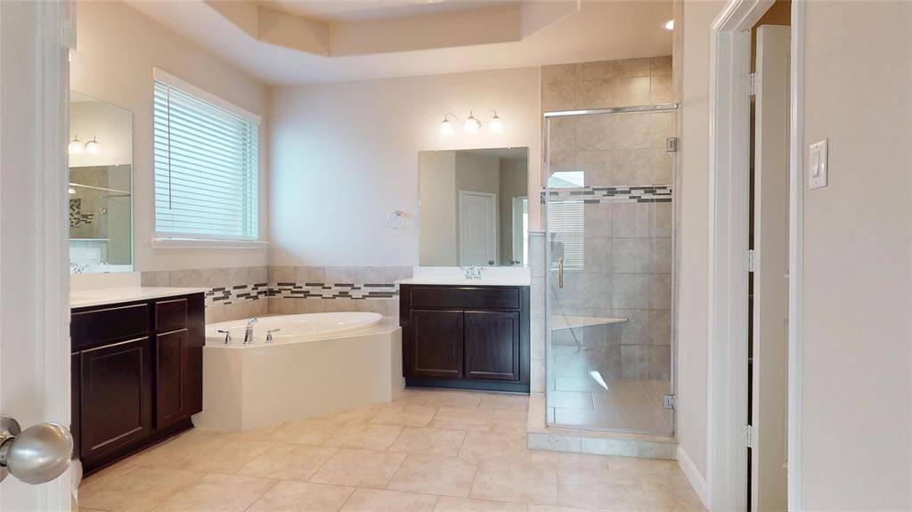 Primary ensuite bathroom with two vanities, standalone shower, soaking tub and walk-in closet.