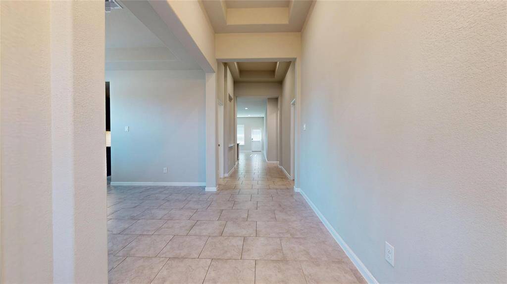 View from the foyer looking toward the rear of the home.  Large, modern tile floors and 10-foot ceilings throughout the living area.