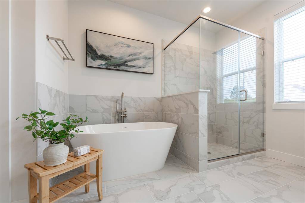 Elegant primary bath featuring a luxurious soaking tub and sleek glass-enclosed shower, perfect for relaxation and style.
