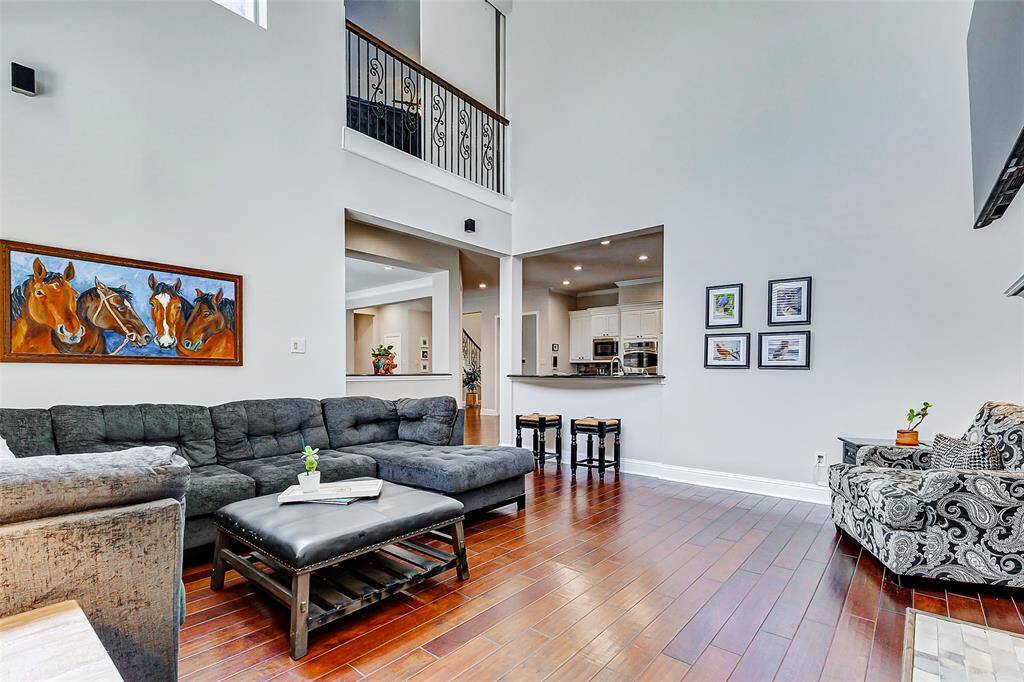 The spacious living room boasts soaring ceilings that create an open, airy feel, while abundant natural light fills the space, highlighting the stunning wood floors. A beautiful gaslog fireplace serves as a focal point, adding both warmth and charm to this inviting area.