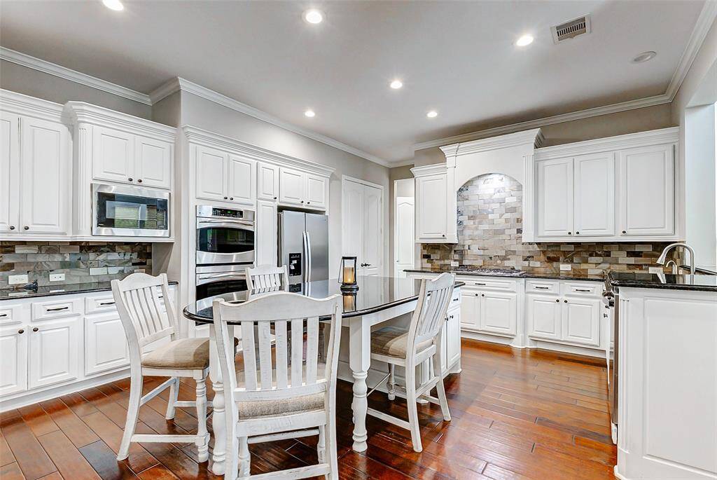 This spacious kitchen is a dream for any home chef, offering ample storage with elegant white cabinetry that keeps everything organized and within reach. The double ovens and gas range make it ideal for cooking enthusiasts who love to prepare meals with ease and precision. Dark granite countertops create a striking contrast against the cabinetry, providing a durable and refined workspace. Thoughtfully designed for effortless movement and everyday use, this kitchen truly serves as the heart of the home.