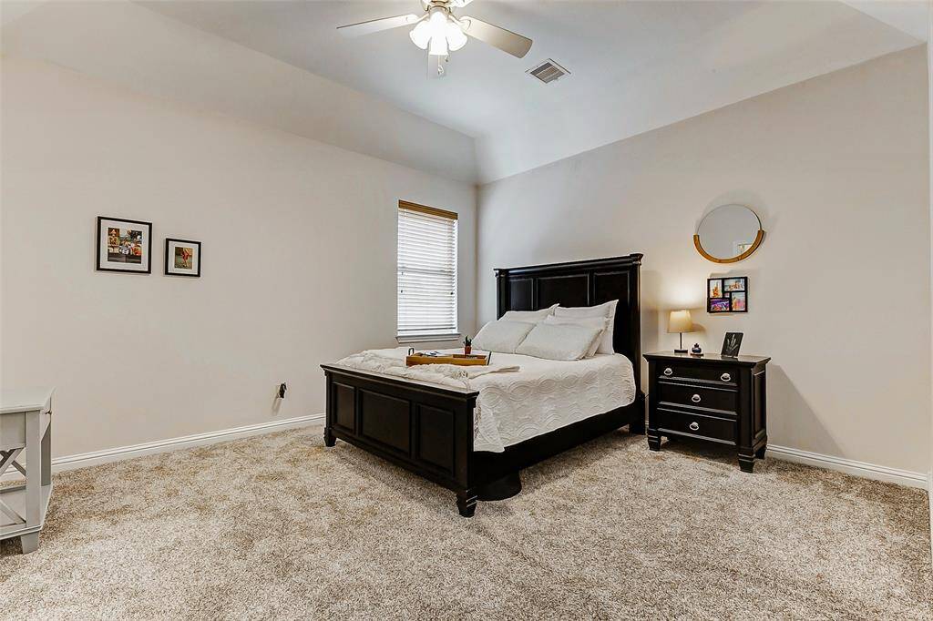Designed with comfort in mind, the bedroom offers a spacious layout complemented by plush carpeting. The large window provides plenty of natural light, and the ceiling fan adds a functional touch, making the space both relaxing and inviting.