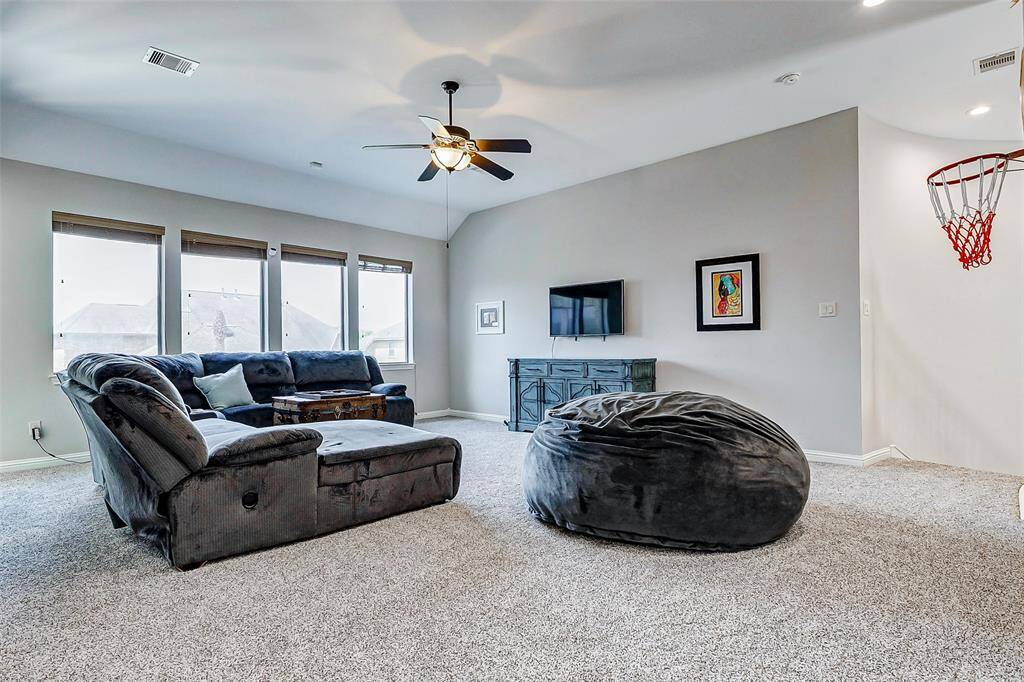 Upon coming upstairs, you’re greeted by the expansive, carpeted area bathed in natural light. The large windows add a sense of openness. It's a comfortable space that provides a cozy alcove feel while still offering plenty of room for recreational activities.