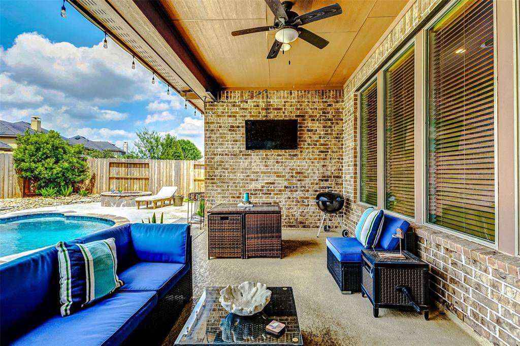 The covered patio by the pool offers the perfect spot for relaxing and unwinding. Equipped with two ceiling fans, it ensures a cool, comfortable experience even during the hot Texas summers. Whether you're enjoying a quiet afternoon or entertaining guests, this shaded retreat provides the ideal outdoor setting.