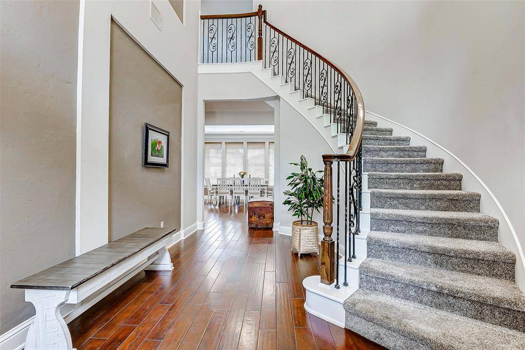 Curved carpeted stairs lead to the second floor, adding a touch of elegance to the home’s interior. The high ceilings throughout the space create a sense of grandeur, making the home feel open, airy, and truly expansive.