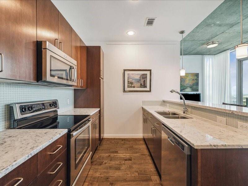 Featuring an open kitchen with a spacious breakfast bar, high-end stainless steel appliances, and elegant marble countertops.