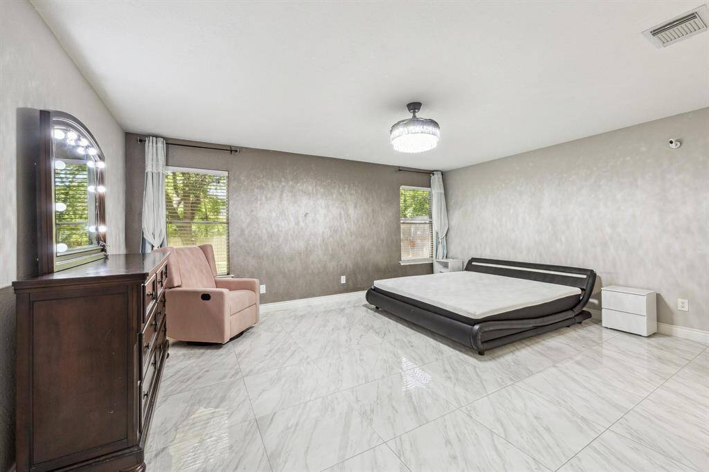 Spacious primary bedroom with custom pendant light fixture.