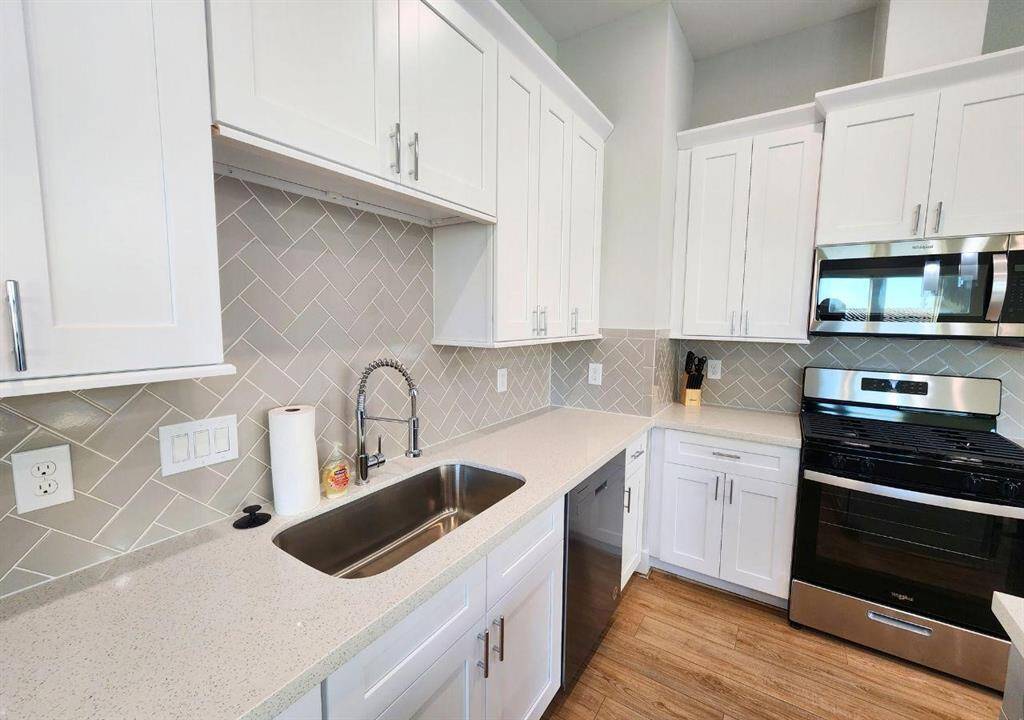 Beautiful quartz counters and herringbone backsplash. Stainless steel fridge and gas stove and microwave.
