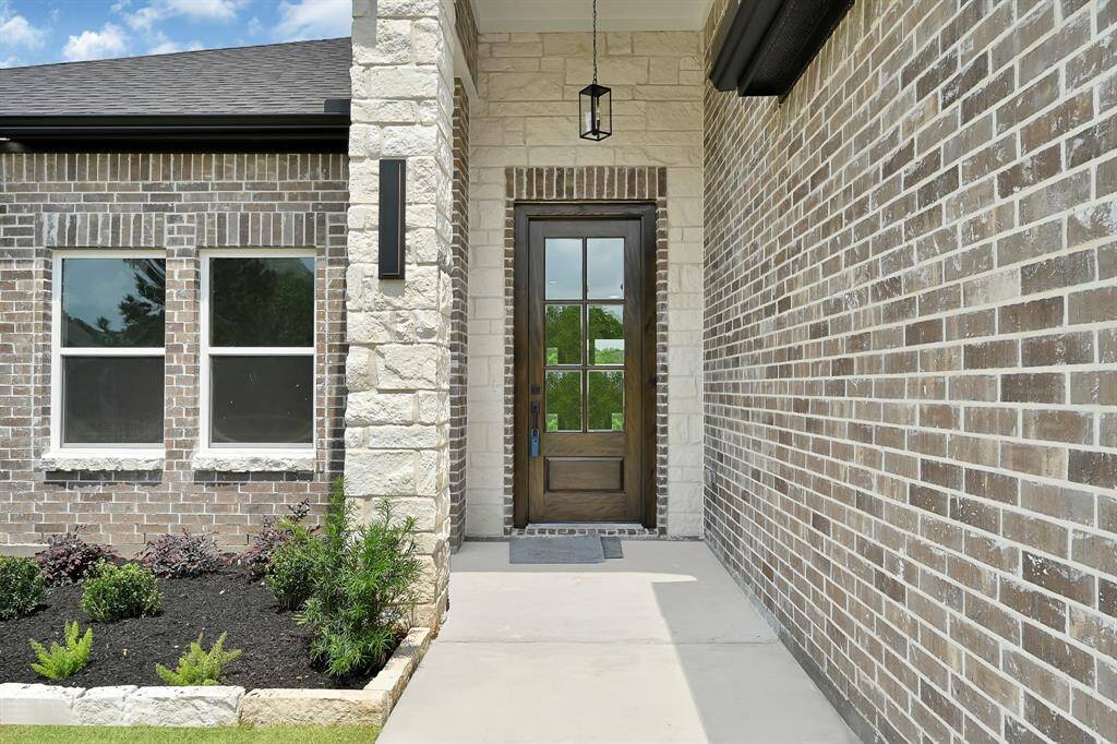 All brick facade with modern sconce lighting and beautiful landscaping