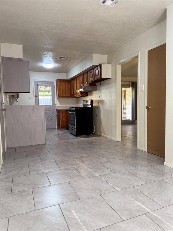 The kitchen features ample cabinet space for all your storage needs, a gas range for precision cooking, a convenient dishwasher, and a double sink for easy clean-up. A door leading directly to the backyard adds extra convenience—perfect for outdoor dining, grilling, or bringing in groceries with ease.