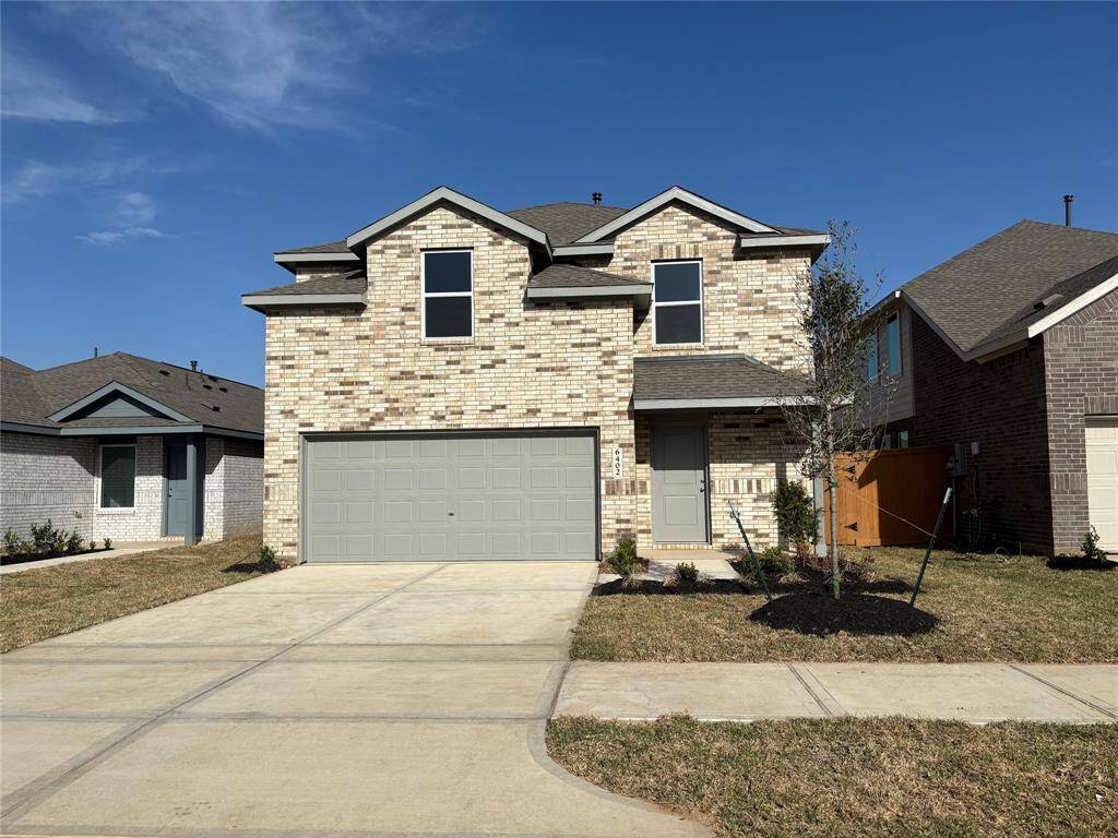 This is a modern two-story home with a brick exterior and a two-car garage. It features a clean, landscaped front yard and a wide driveway. The house has a classic, neutral color scheme with a welcoming entrance.