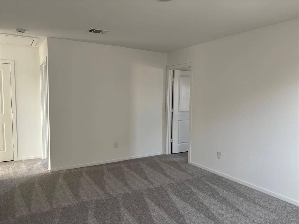 Bright, spacious game room on 2nd floor with clean white walls and new carpet. Features a doorway to the primary bedroom also suitable for a office.