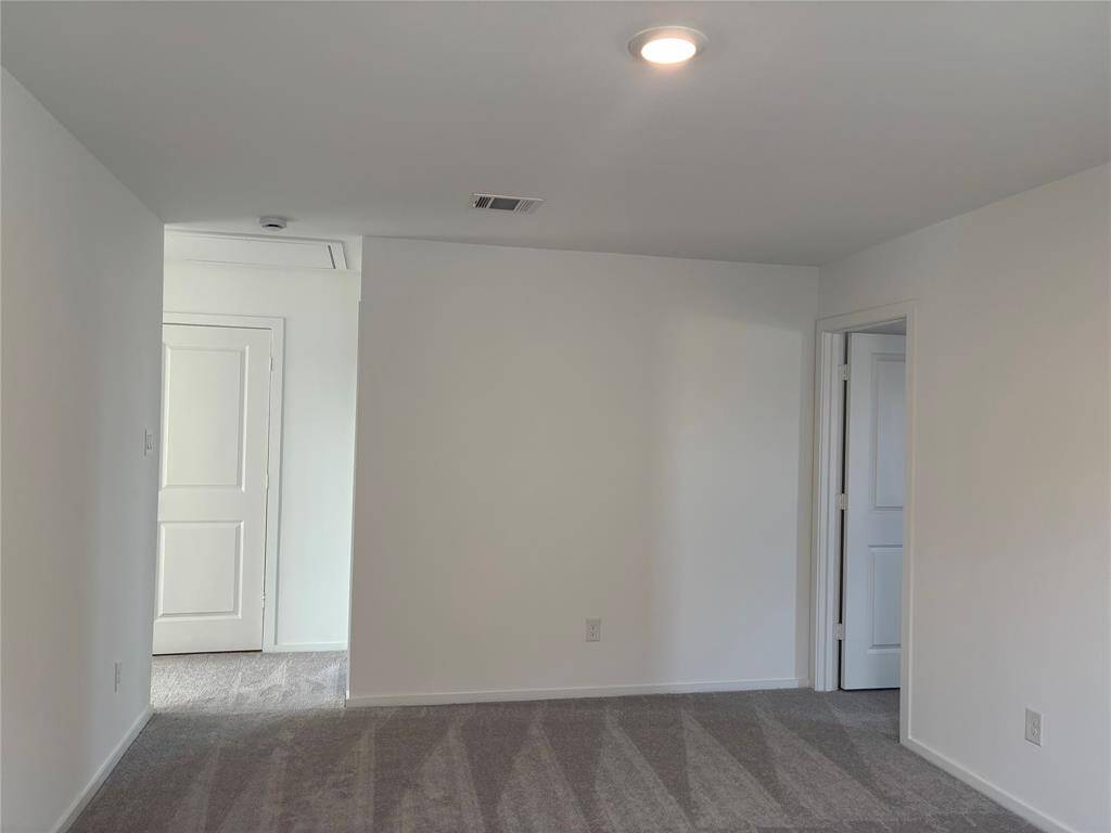 This photo shows a bright, freshly painted game room with light gray carpeting. It features recessed lighting and two doorways leading to adjacent areas, adding to its spacious feel.