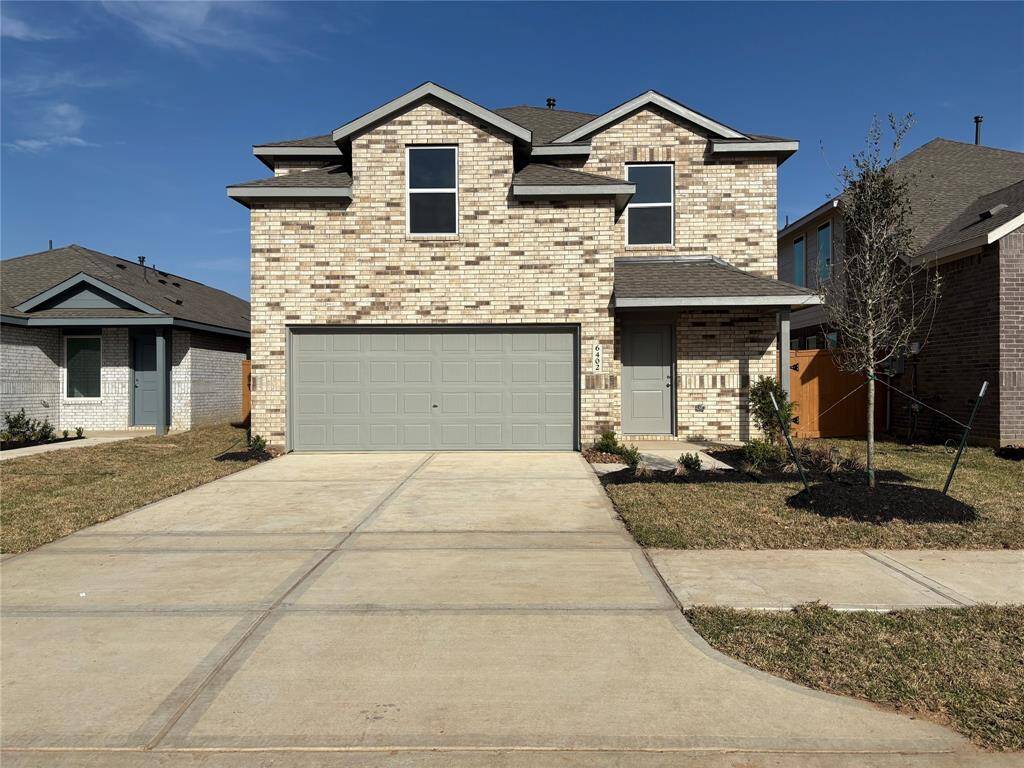 This is a modern two-story brick house with a two-car garage. The home has a clean, contemporary design with a well-maintained front yard and a paved driveway.