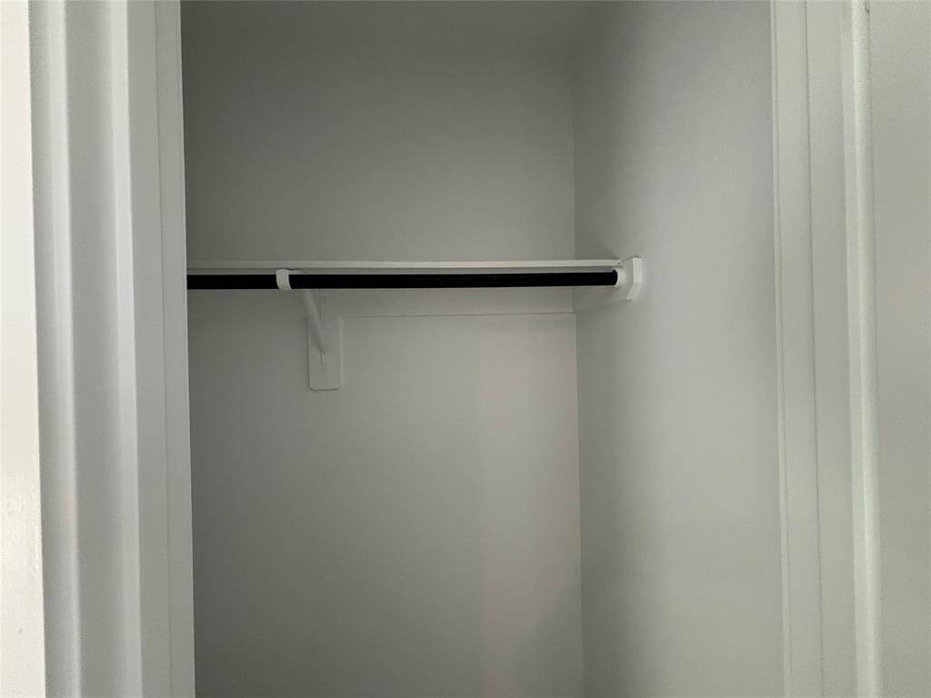 This photo shows a small, empty closet with a single hanging rod and a clean, white interior.