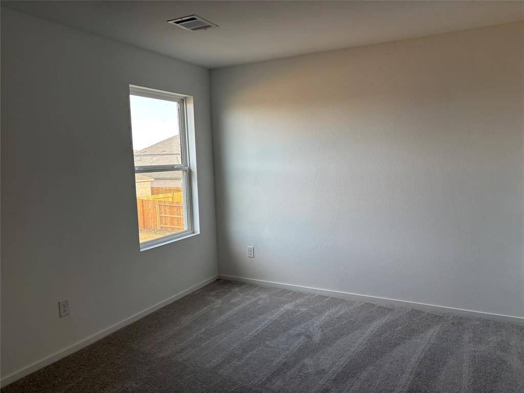 This photo shows a bright, empty room with neutral-colored carpet and walls. It features a single window, allowing natural light to fill the space. Perfect for a bedroom or home office.