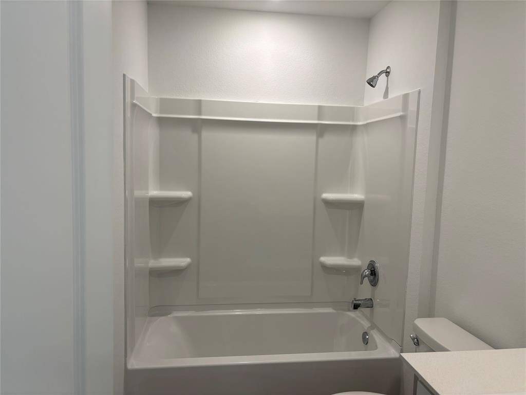 This is a modern, clean second bathroom on 2nd floor featuring a shower-tub  with built-in shelving and a sleek white finish.