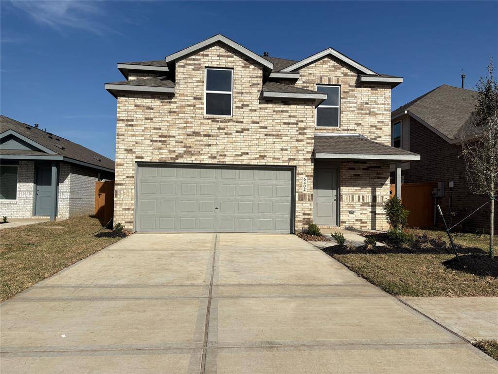 This is a modern two-story home with a brick exterior and a two-car garage. It features a clean driveway, simple front landscaping, and a welcoming porch area.