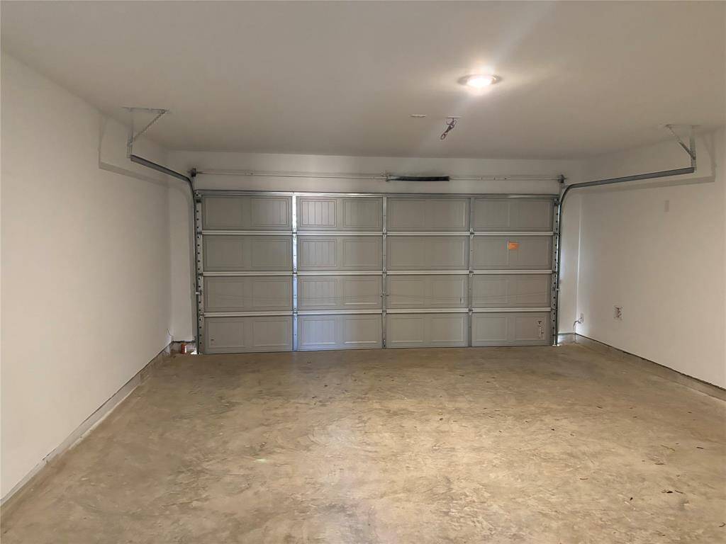 This photo shows a spacious, 2 car clean garage with a concrete floor and a large overhead door, ideal for parking or storage. Garage automatic opener will be installed.