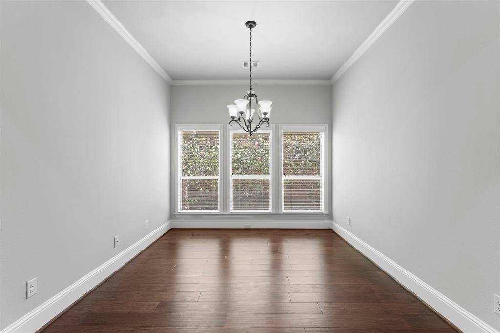 Elegant formal dining room featuring rich wood floors, abundant natural light, and a stylish chandelier.