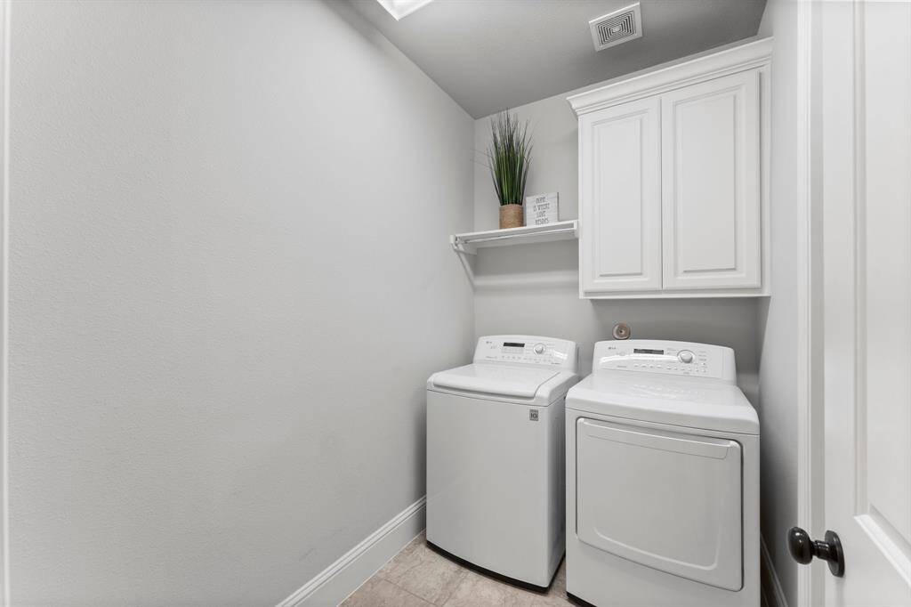 Sleek laundry room with cabinet and a washer and dryer that stays with the home.