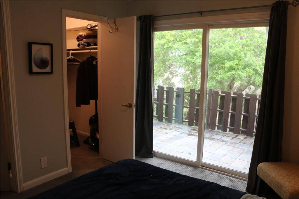 Primary bedroom has private balcony with views of lush oak trees and neighboring condos