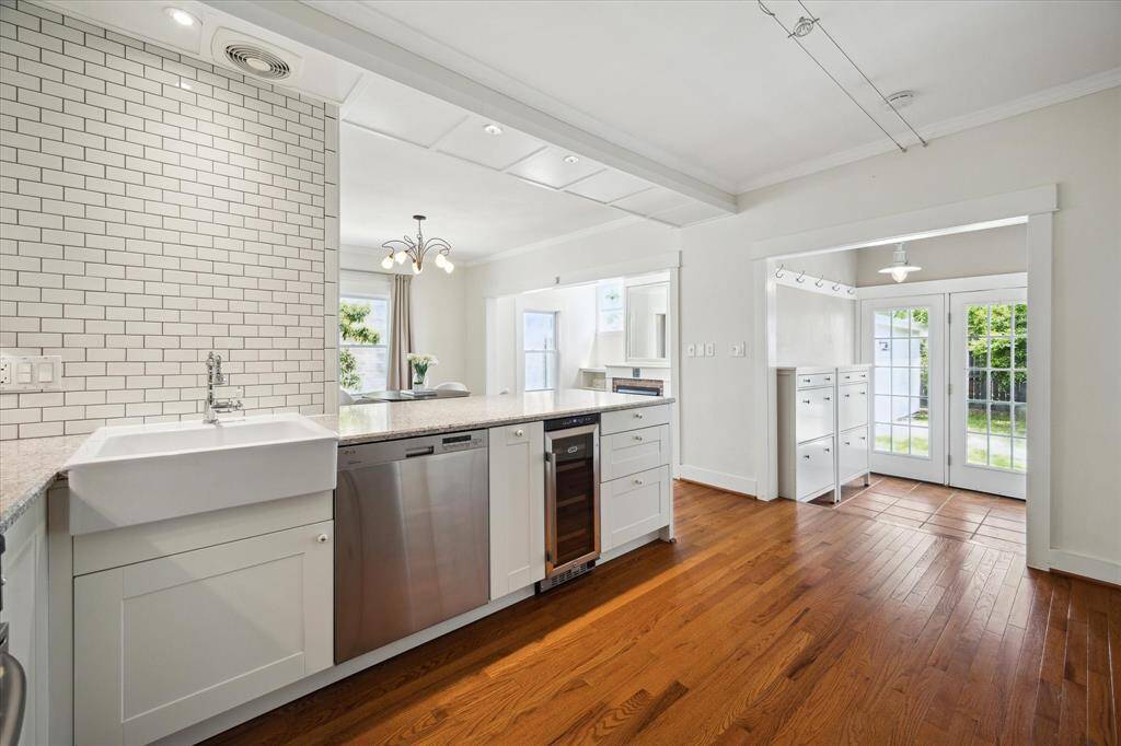 Bright and functional kitchen with a farmhouse sink, subway tile wall, and open flow toward the backyard and additional storage zone. A practical space with a clean and connected layout.