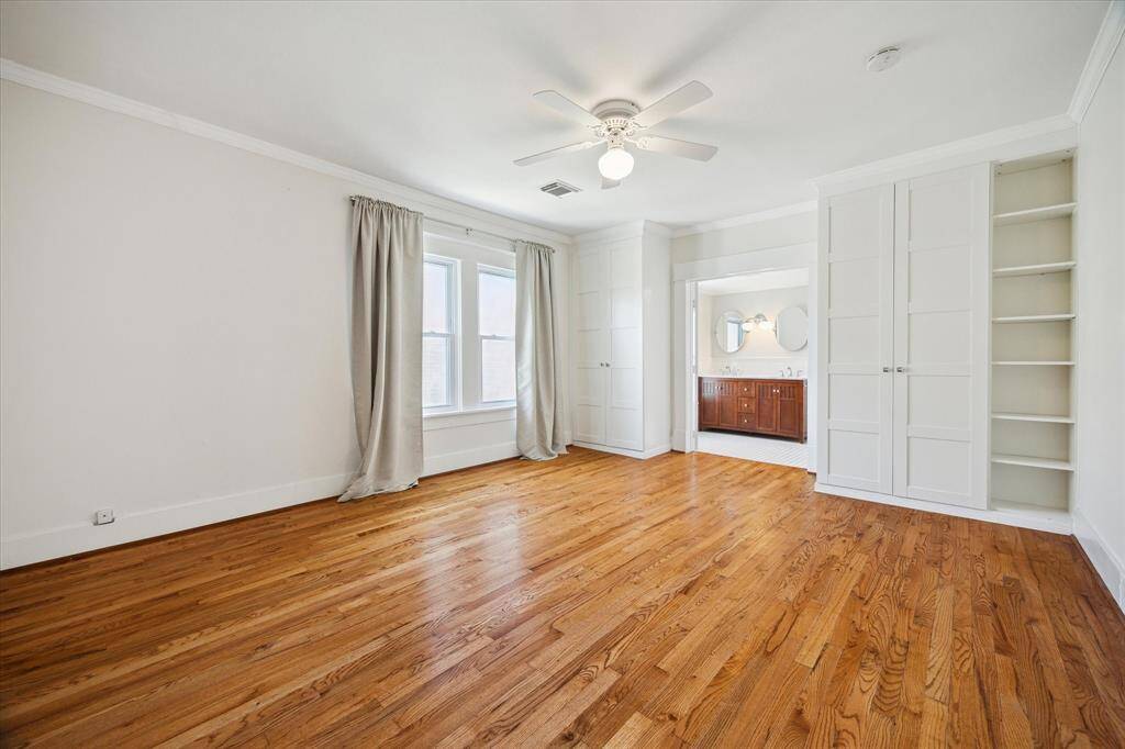 Spacious upstairs bedroom with built-in shelving, a wall of closets, and a private vanity area. Offers both comfort and convenience in a quiet retreat.