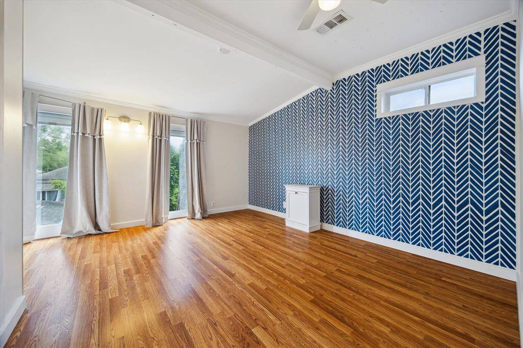 Expansive upper-level bedroom with vaulted ceiling, wall of windows, and built-in storage. A flexible space for restful living.