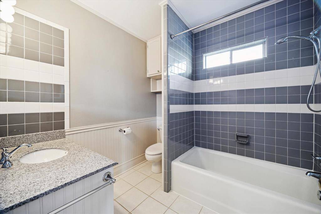 Upper-level bathroom featuring a tiled tub-shower combo and a wide vanity. Offers comfort and function with a modern layout.