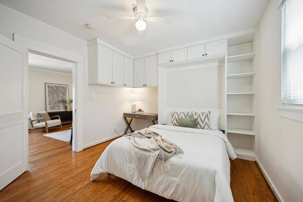 Main floor bedroom includes built-in shelving, upper cabinetry, and a custom Murphy bed. Perfect for a guest room or compact office conversion.