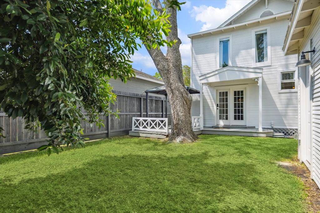 A view of the backyard looking toward the back of the home, showing French doors and multiple access points. Great for indoor-outdoor flow.