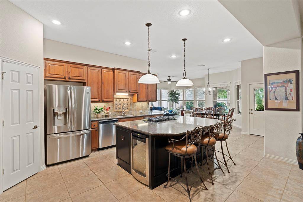 The large center island features a breakfast bar, gas cooktop, and built-in wine cooler.