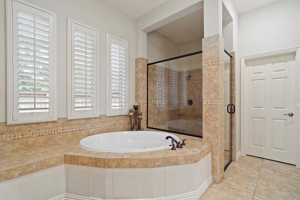 Unwind in the jetted soaking tub, where a wall of windows fills the space with soft natural light, while shutters offer privacy when needed.