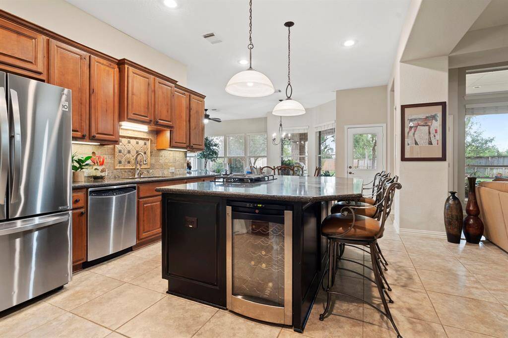 The well-appointed kitchen features Silestone countertops, a walk-in pantry, an island with a gas cooktop, pot & pan drawers, a breakfast bar, custom cabinetry, and MORE!