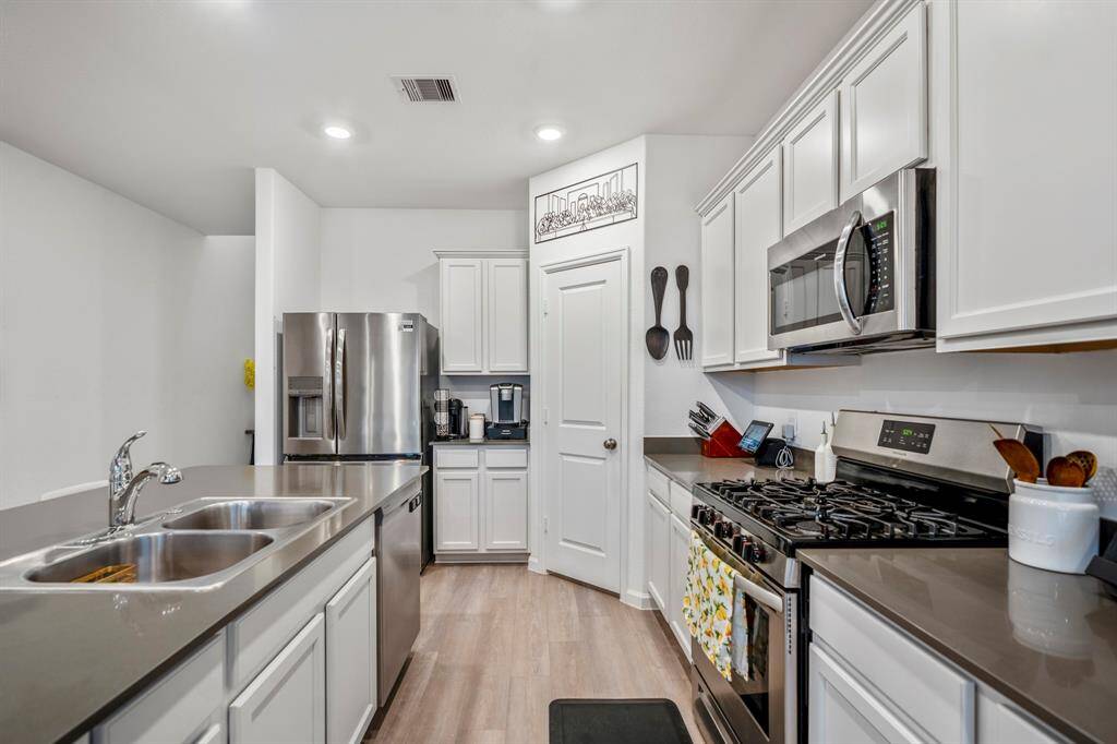 All stainless steel appliances and quartz counters in this light and bright kitchen. Closed door is the pantry.